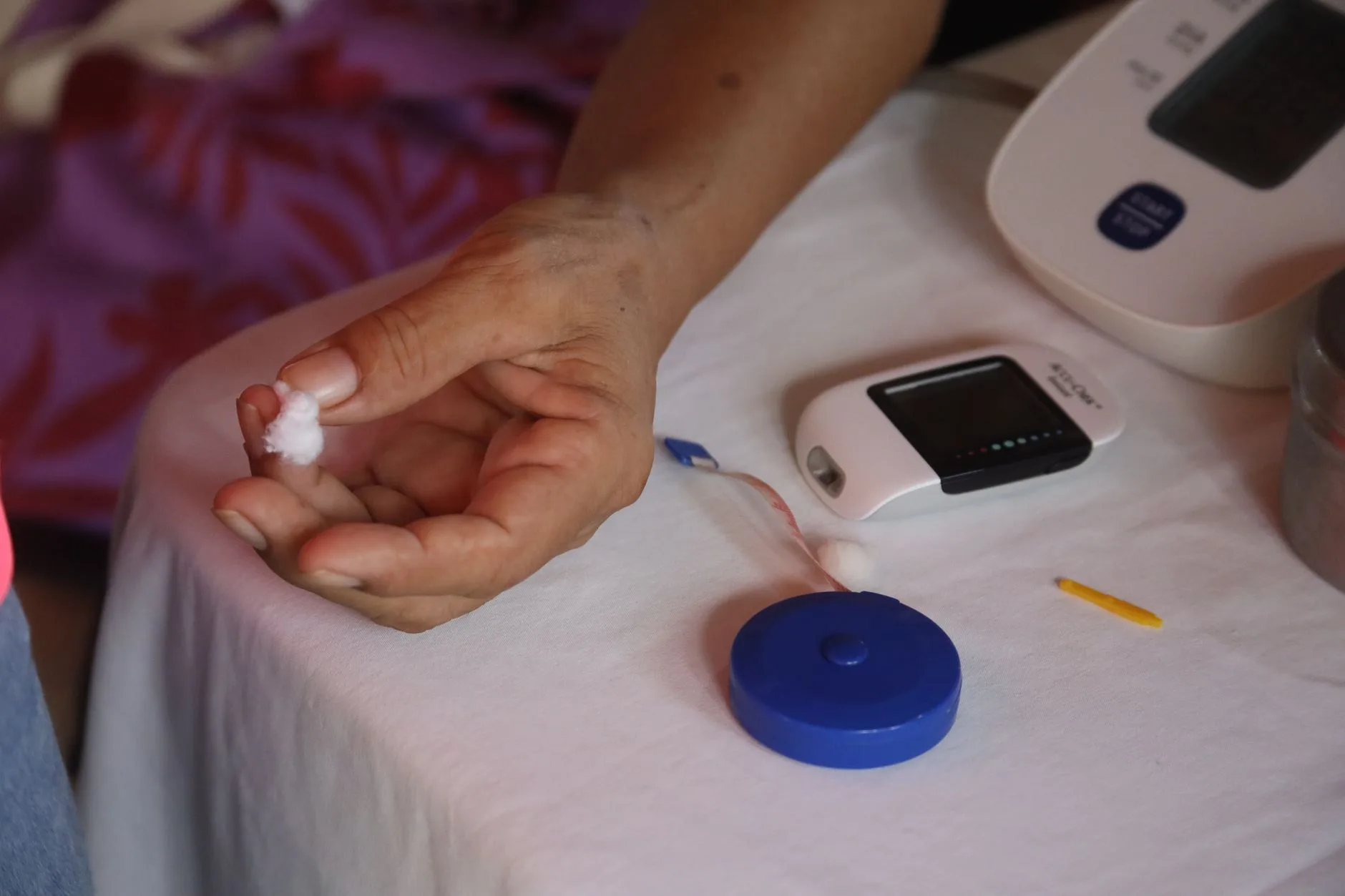 person checking blood glucose with monitor and supplement on table