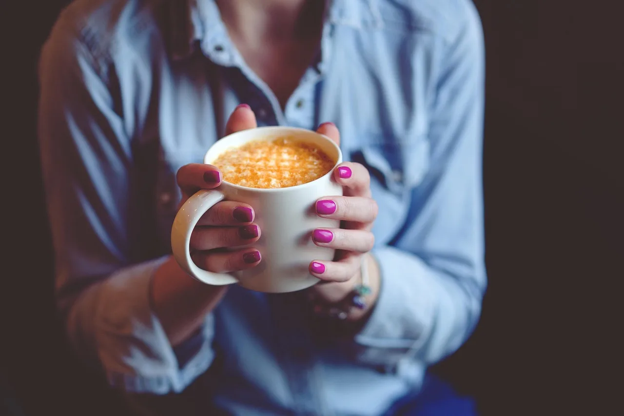 person holding coffee cup feeling anxious jittery