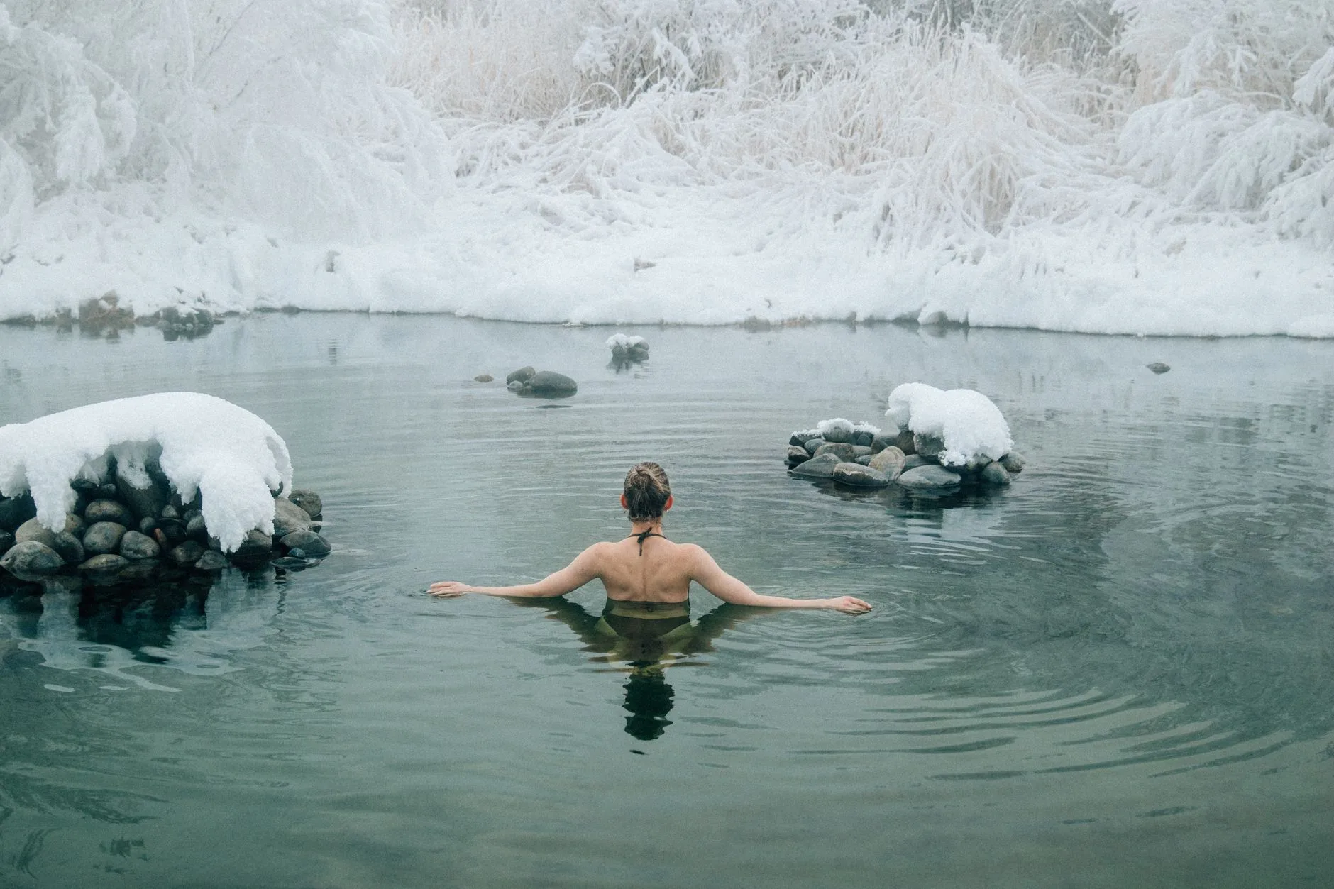 person immersed in outdoor ice bath