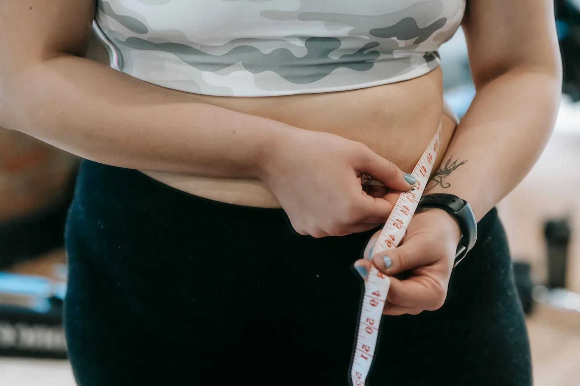 middle aged woman measuring waist with tape