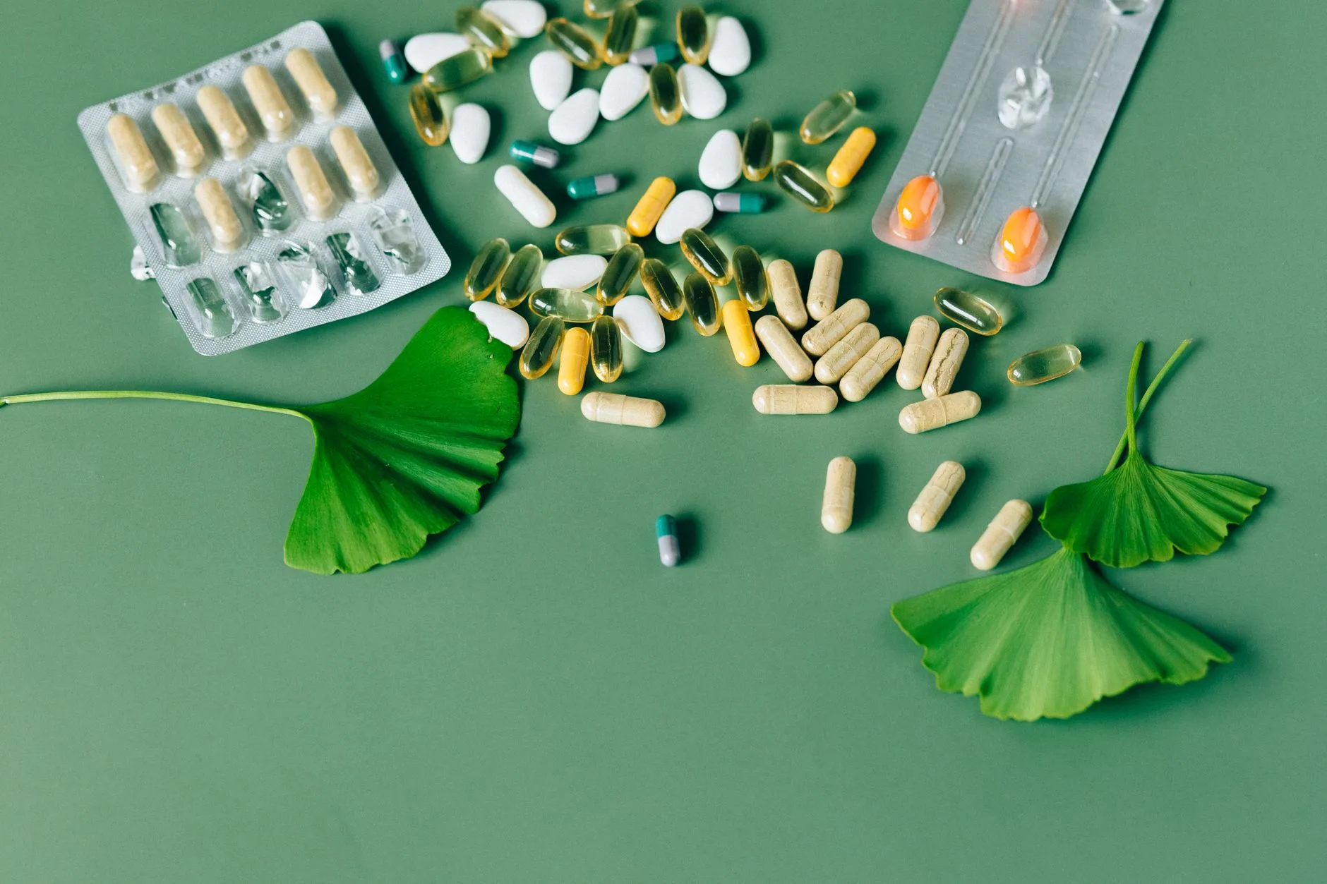 green tea leaves and capsules on wooden table