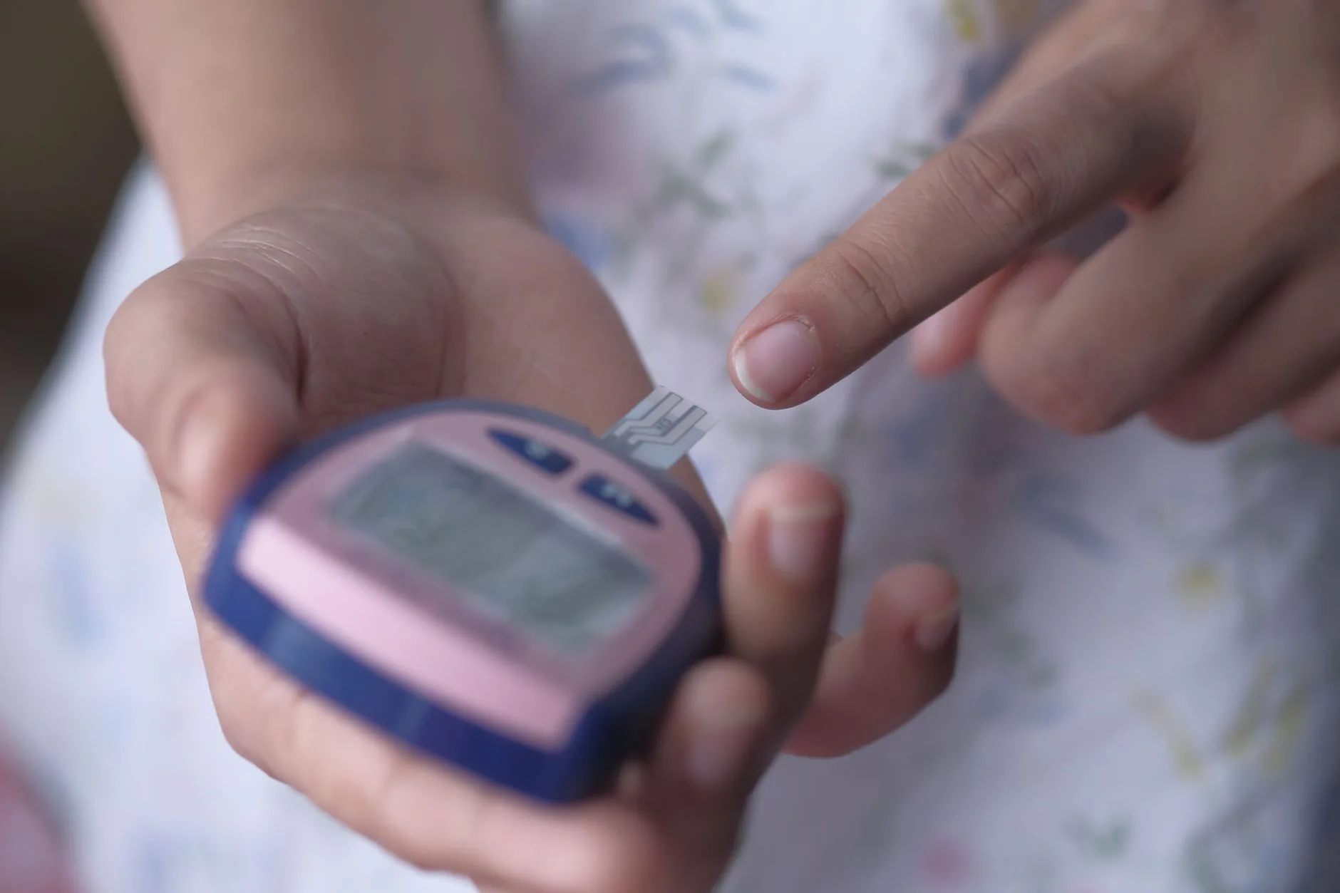 person checking blood sugar with glucometer at home